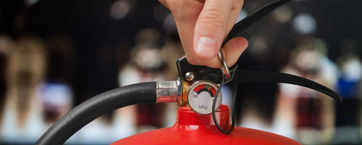 Hand pulling pin out of fire extinguisher