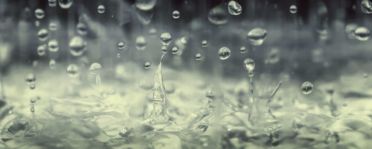 Closeup of raindrops falling into a puddle