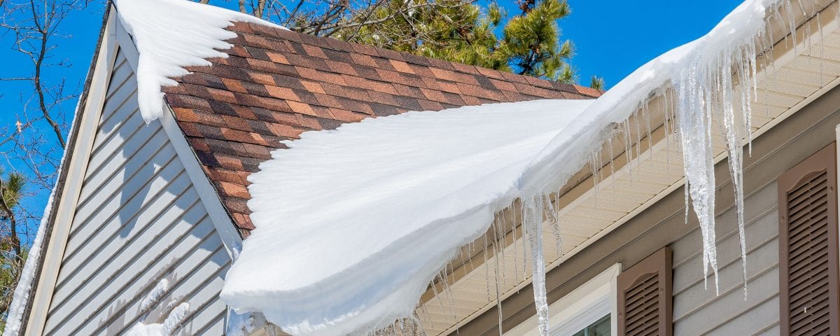 Roof with damaged shingles covered in snow