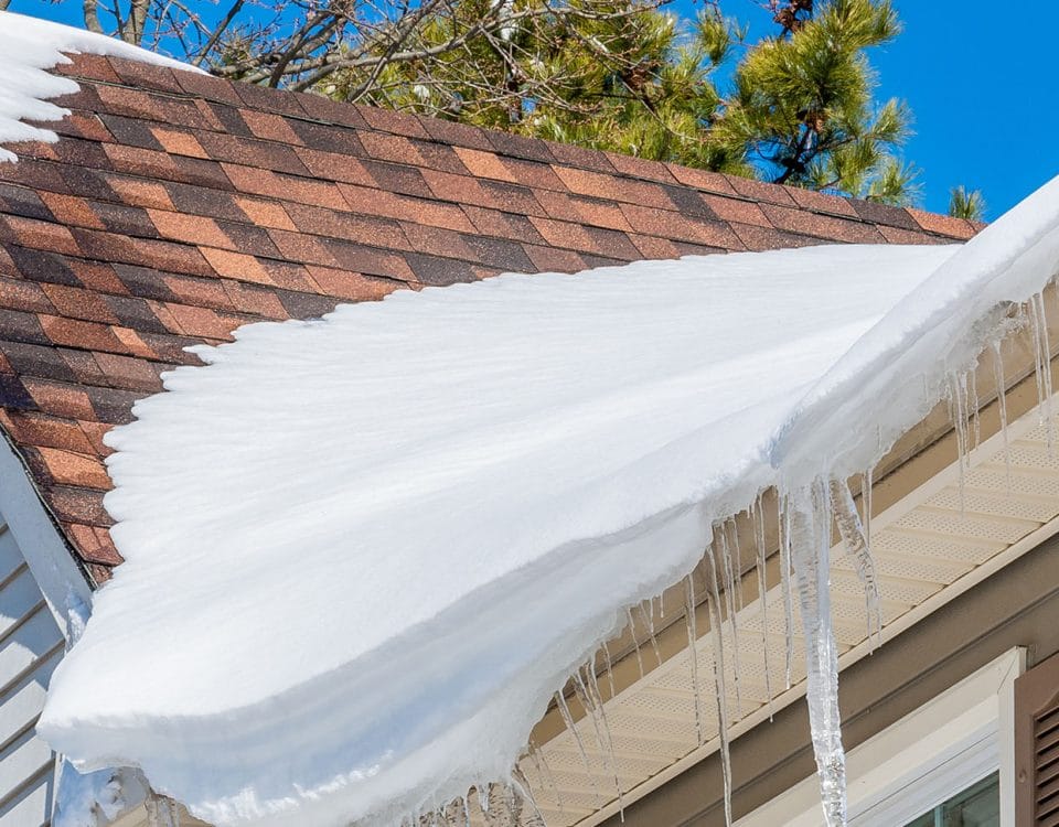 Roof with damaged shingles covered in snow