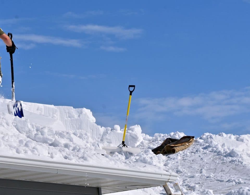 Snow is being removed from a roof with a shovel after a heavy snowfall