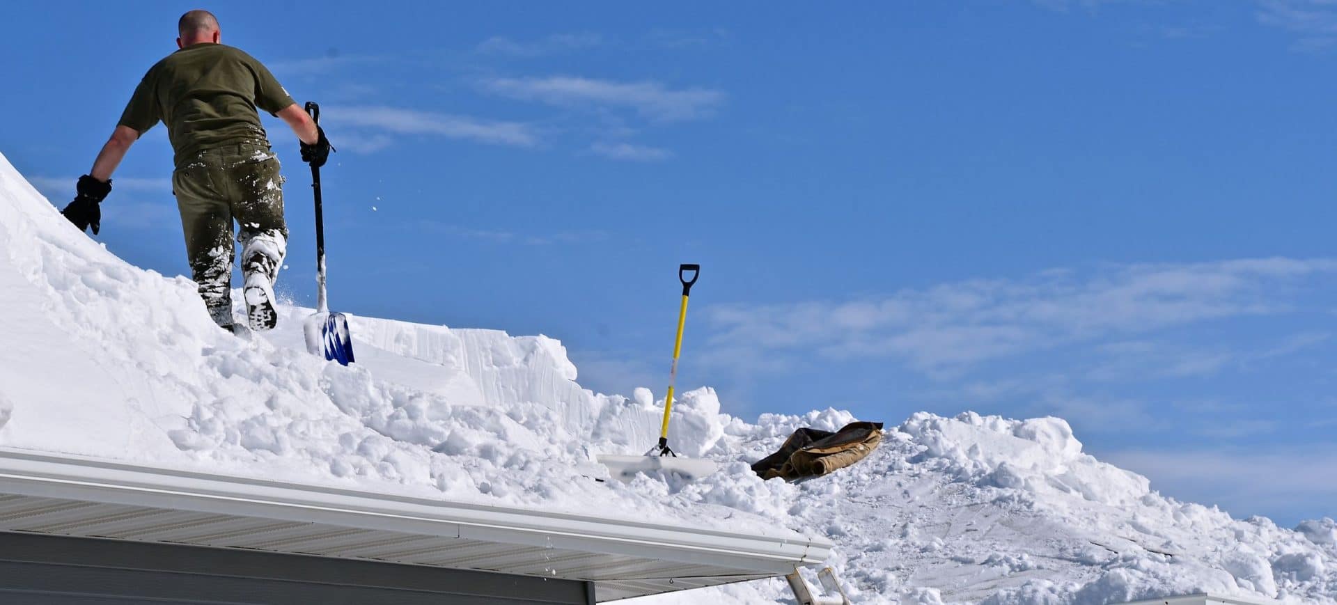 Snow is being removed from a roof with a shovel after a heavy snowfall