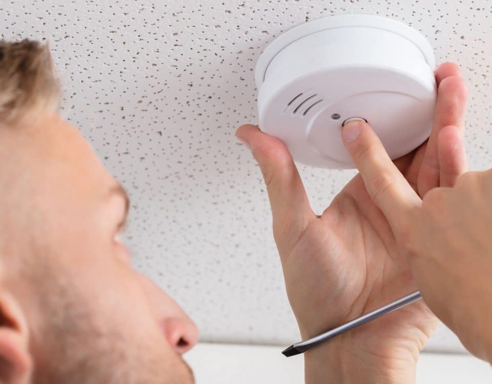 A Person's Hand Installing Smoke Detector On Ceiling Wall At Home