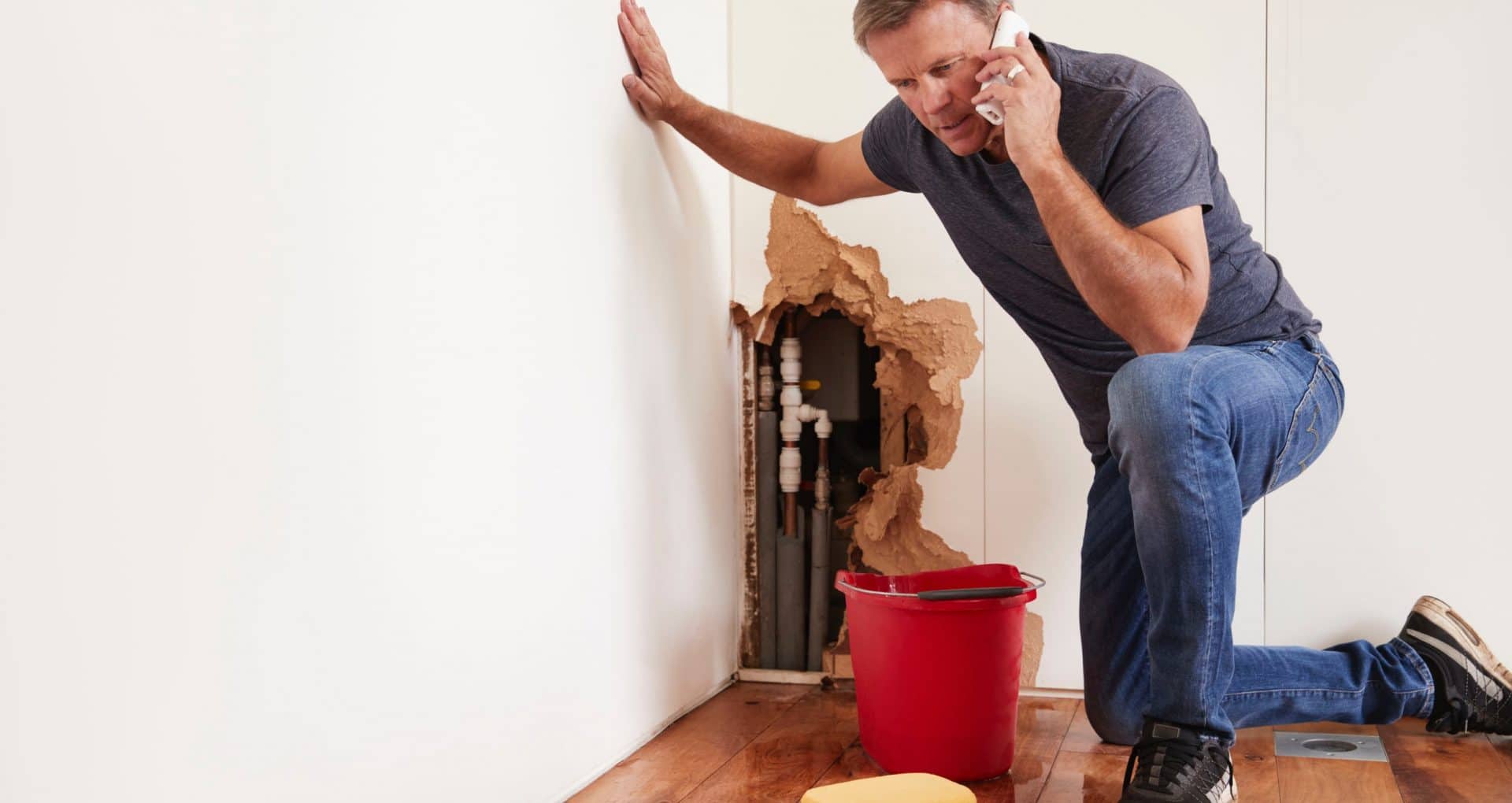 Middle aged man with a burst water pipe phoning for help