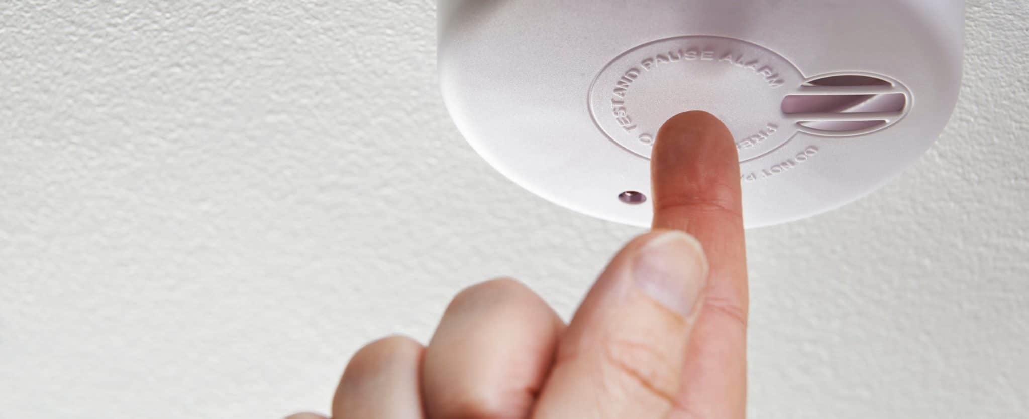 Close Up Of Hand Testing Domestic Smoke Alarm