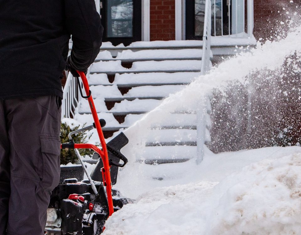 Man blowing snow and clearing the entrance of a house after a winter storm