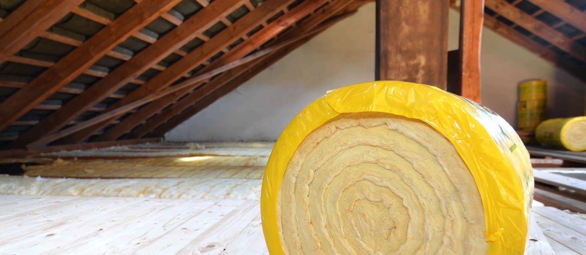 A roll of insulating glass wool on an attic floor