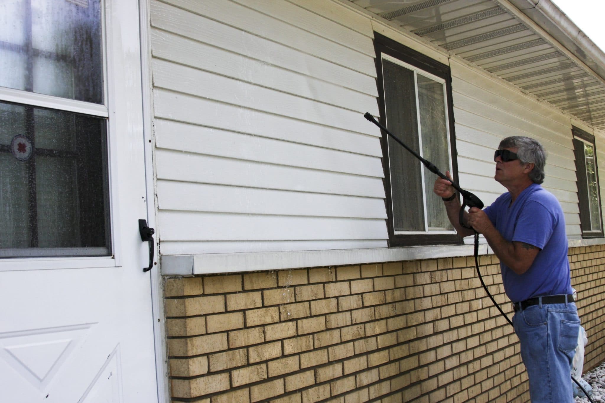 Home owner pressure washing the siding of his house