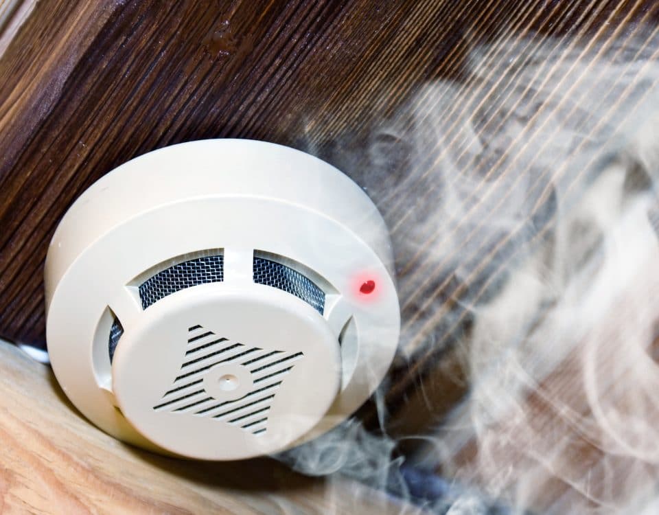 Smoke detector on a ceiling surrounded by smoke
