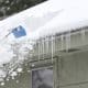 Person removing snow from the roof of a home