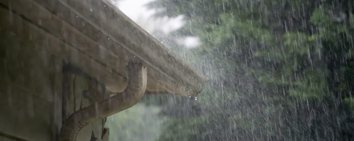 Rain pouring down on the roof and gutter of a home