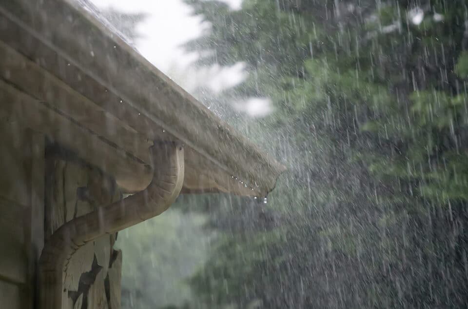 Rain pouring down on the roof and gutter of a home