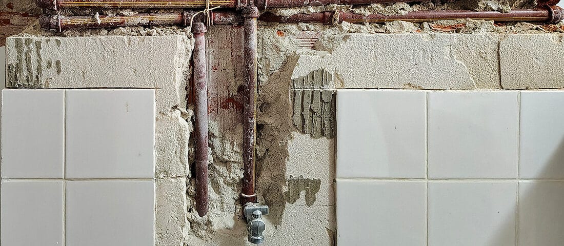 Tile surface of a wall broken away to expose plumbing