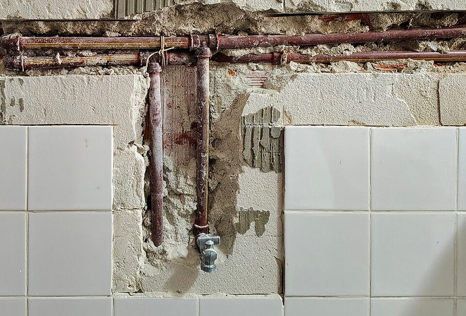 Tile surface of a wall broken away to expose plumbing