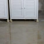 Water leaking on a basement floor and running underneath cabinets