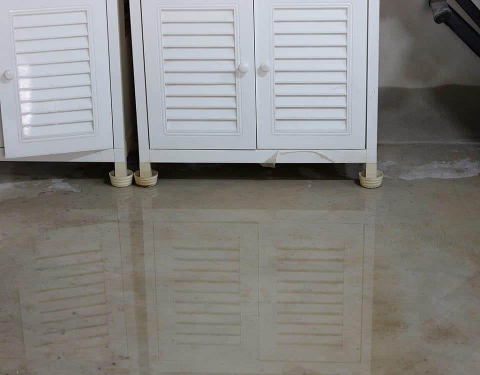 Water leaking on a basement floor and running underneath cabinets